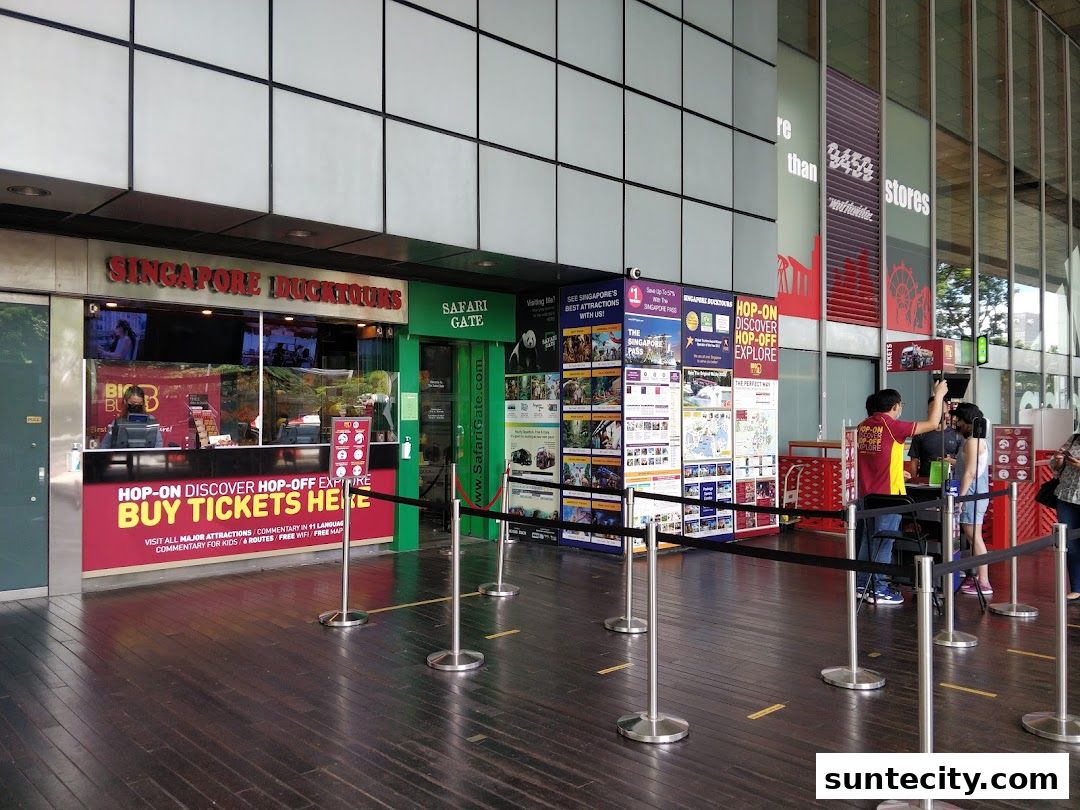 The Singapore DUCKtours ticket counter with promotional posters and staff assisting customers.