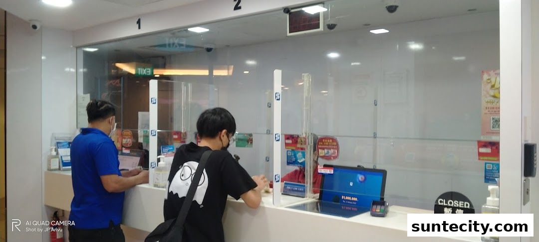 Two customers interact with staff behind a counter at Singapore Pools.