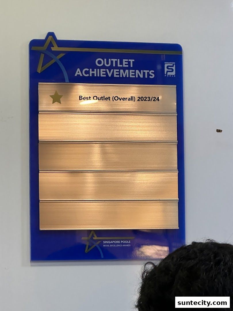 A plaque displaying 'Best Outlet (Overall) 2023/24' award for Singapore Pools.