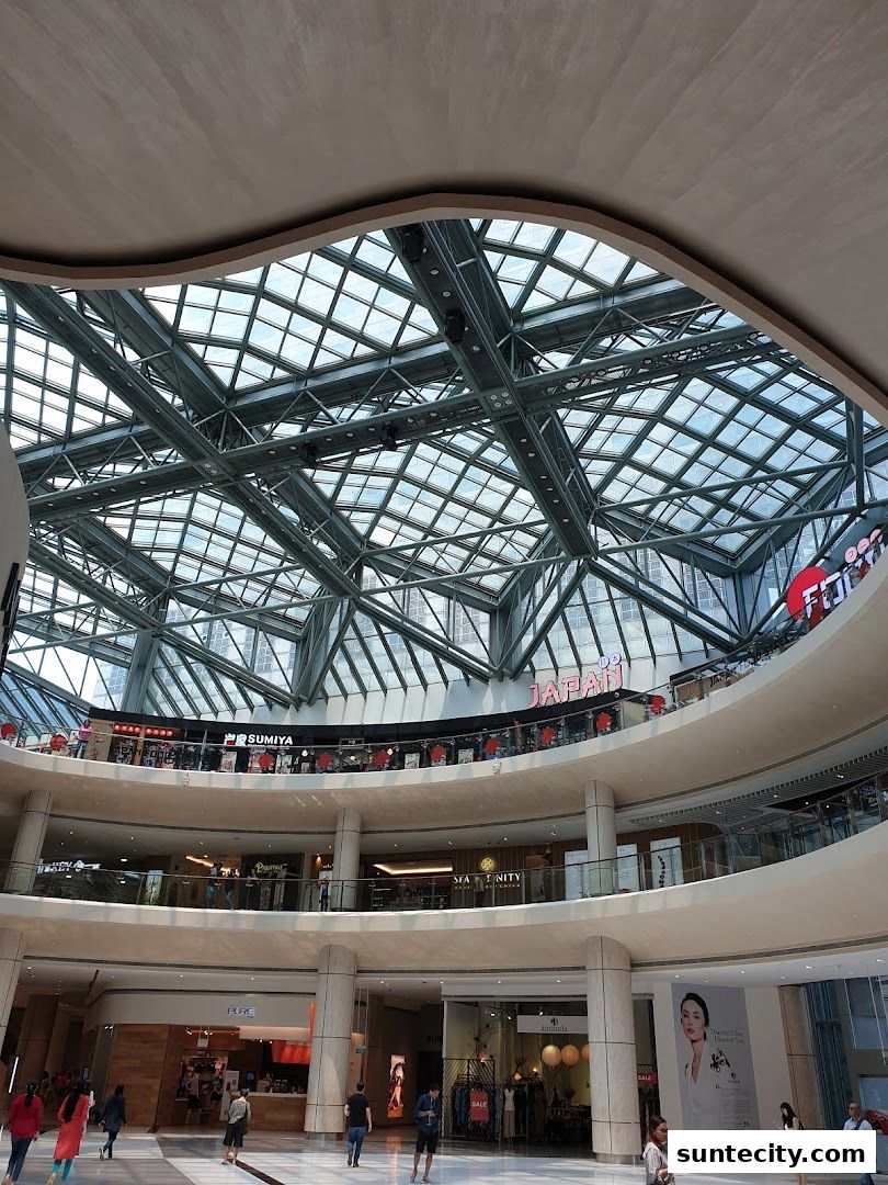 Interior view of a modern shopping mall with multiple levels and a large glass ceiling.