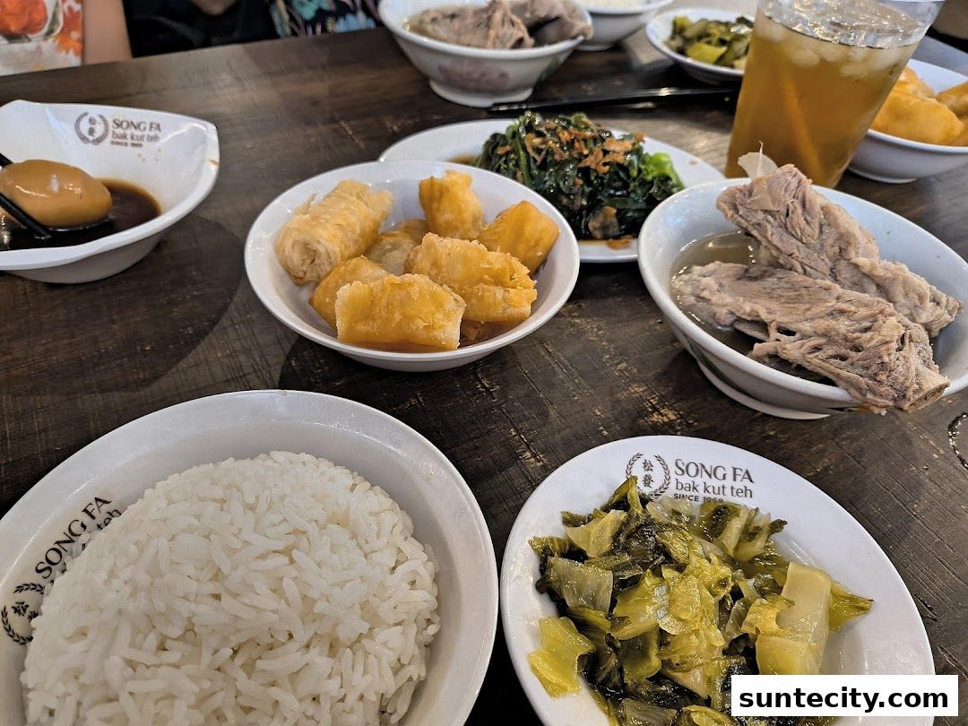 A table laden with various dishes from Song Fa Bak Kut Teh, including rice, meat, and side dishes.