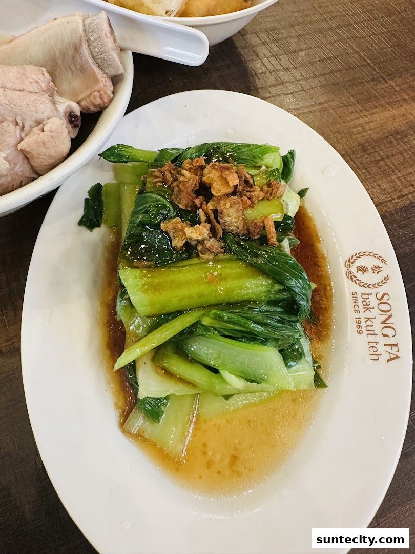 A plate of stir-fried green vegetables with crispy fried shallots, served with pork ribs.