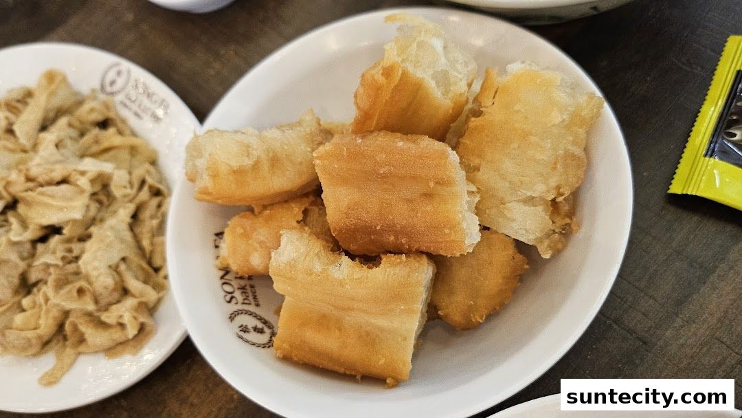 A close-up shot of fried dough sticks and dried tofu skin served in white bowls.
