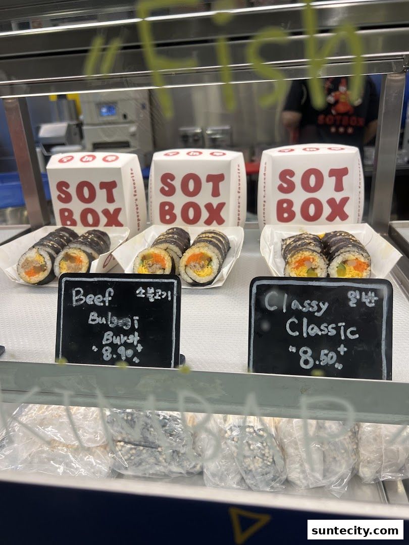 A display of Korean gimbap rolls with branded packaging and price labels.