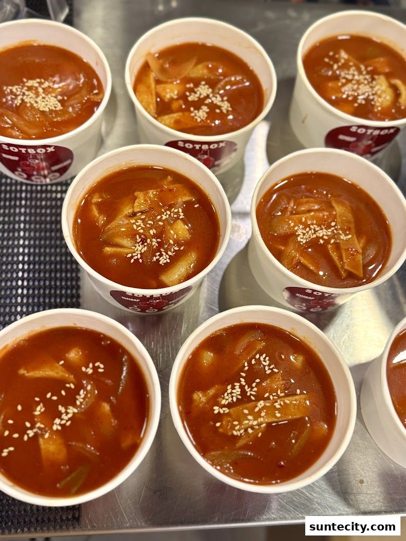 Several cups of Korean tteokbokki, a spicy rice cake dish, are arranged on a surface.