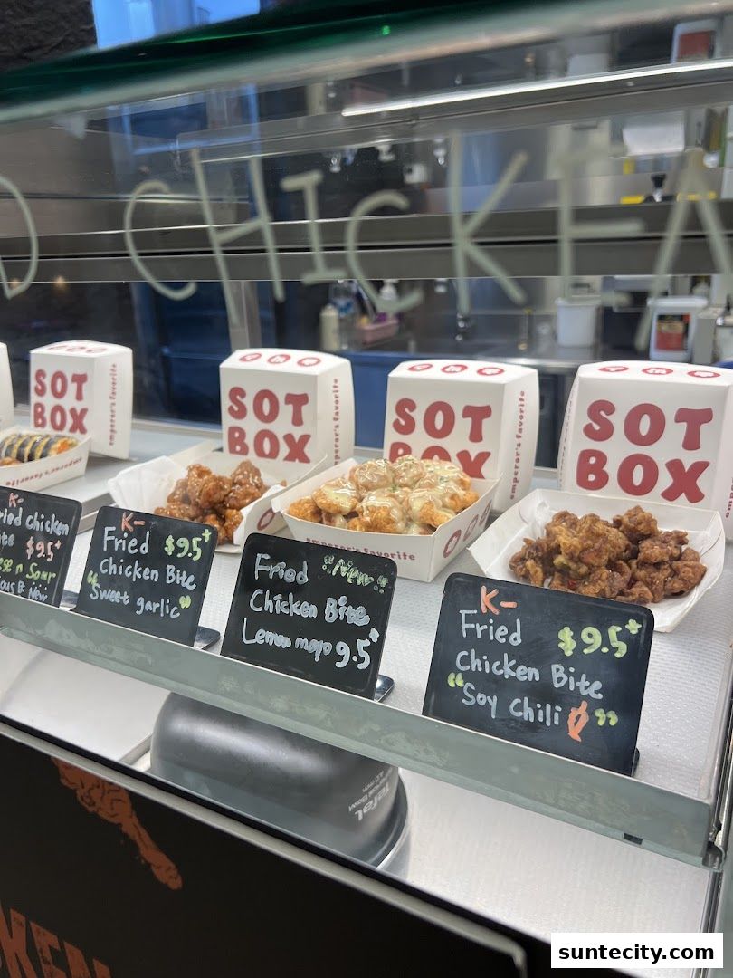 A display case filled with various flavors of fried chicken bites and SOTBOX packaging.
