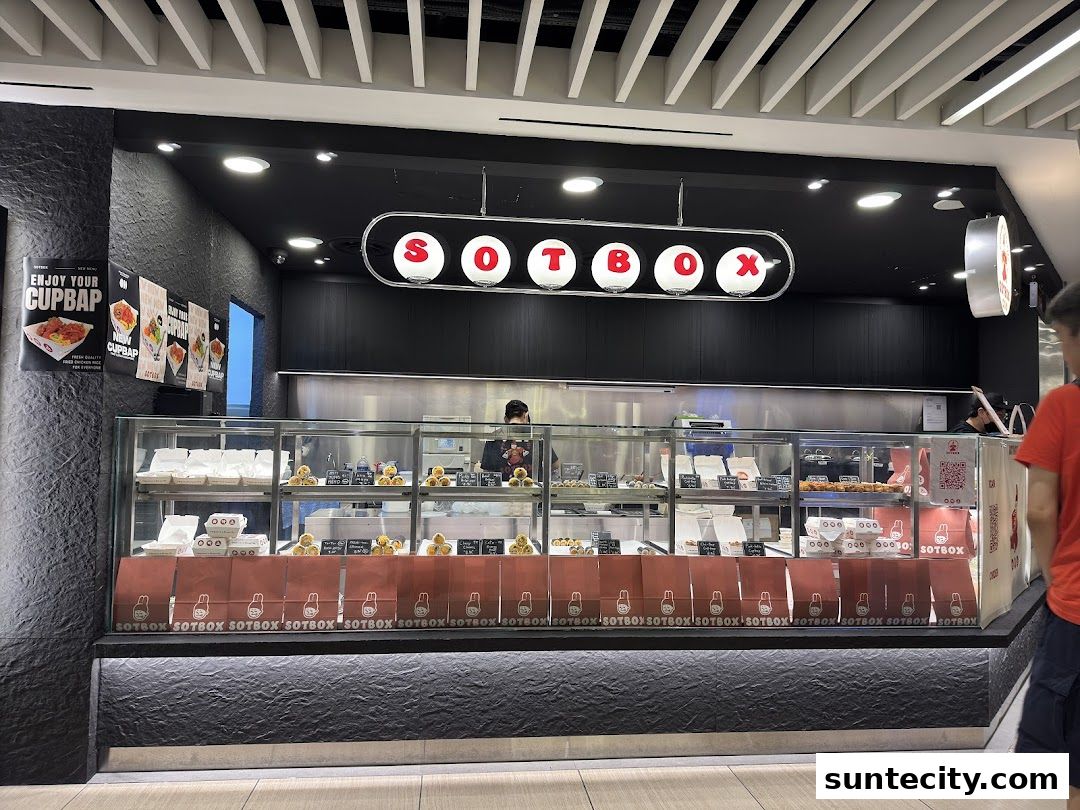 The SOTBOX shop front displays a variety of food items in a display case and branded bags.