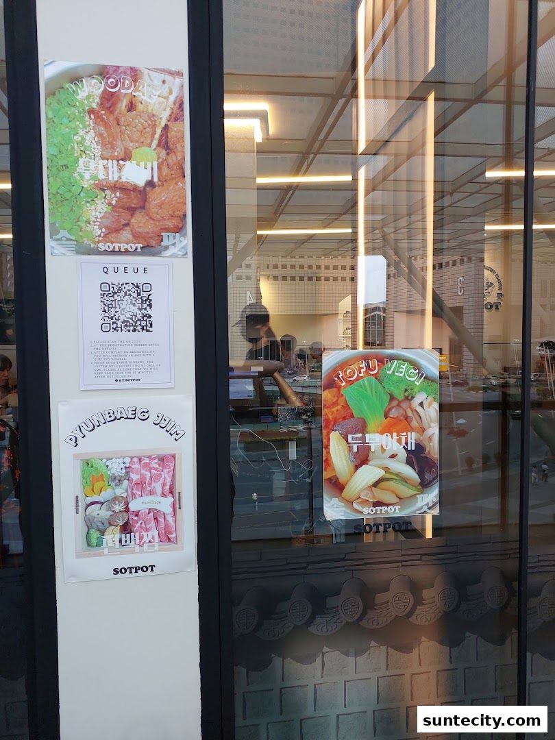 Shop front with posters showcasing food items and a QR code for queuing.