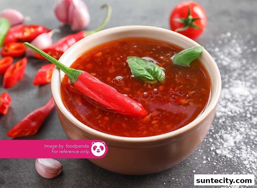 A bowl of spicy red sauce with chili peppers, garlic, and basil leaves.