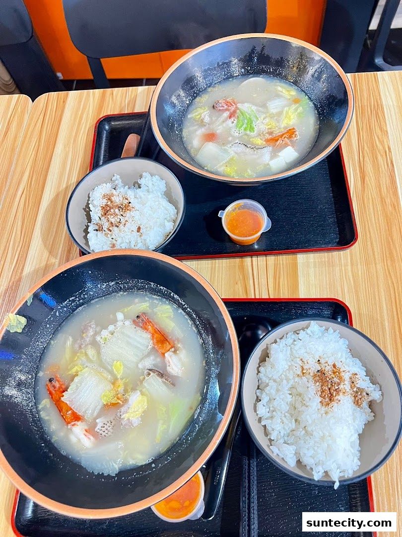 Two bowls of hearty soup with rice and a side of chili sauce.
