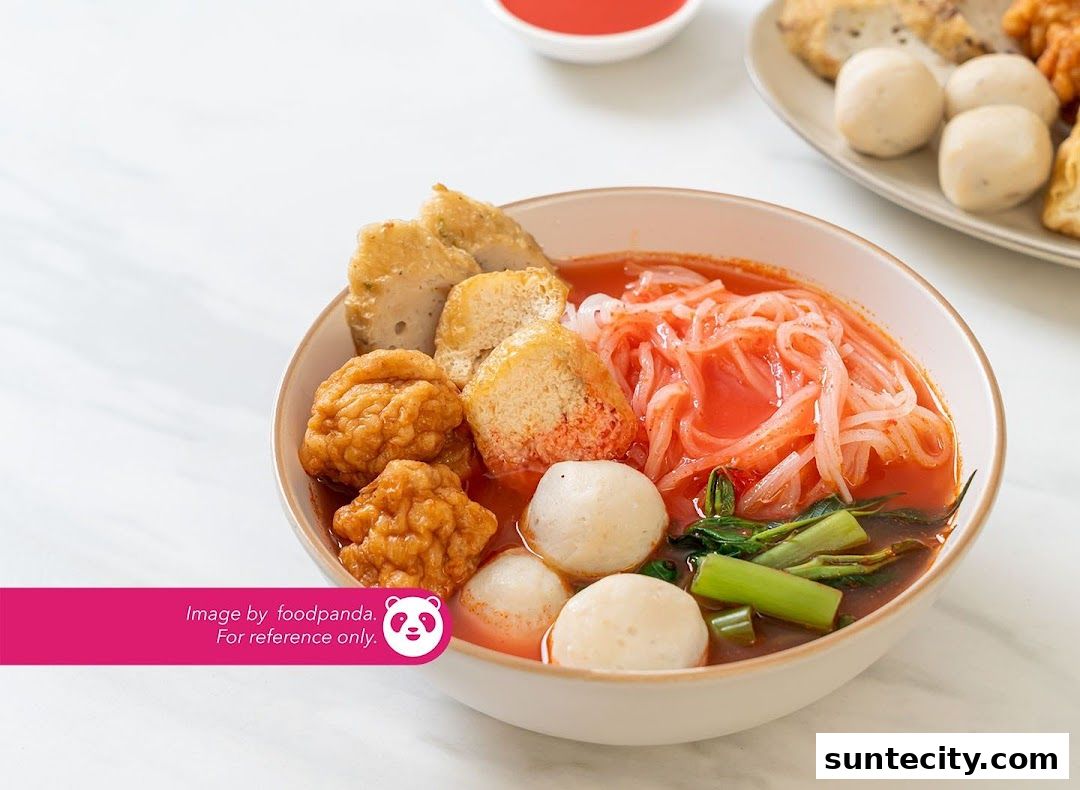 A bowl of pink noodle soup with various fish balls and fried tofu.