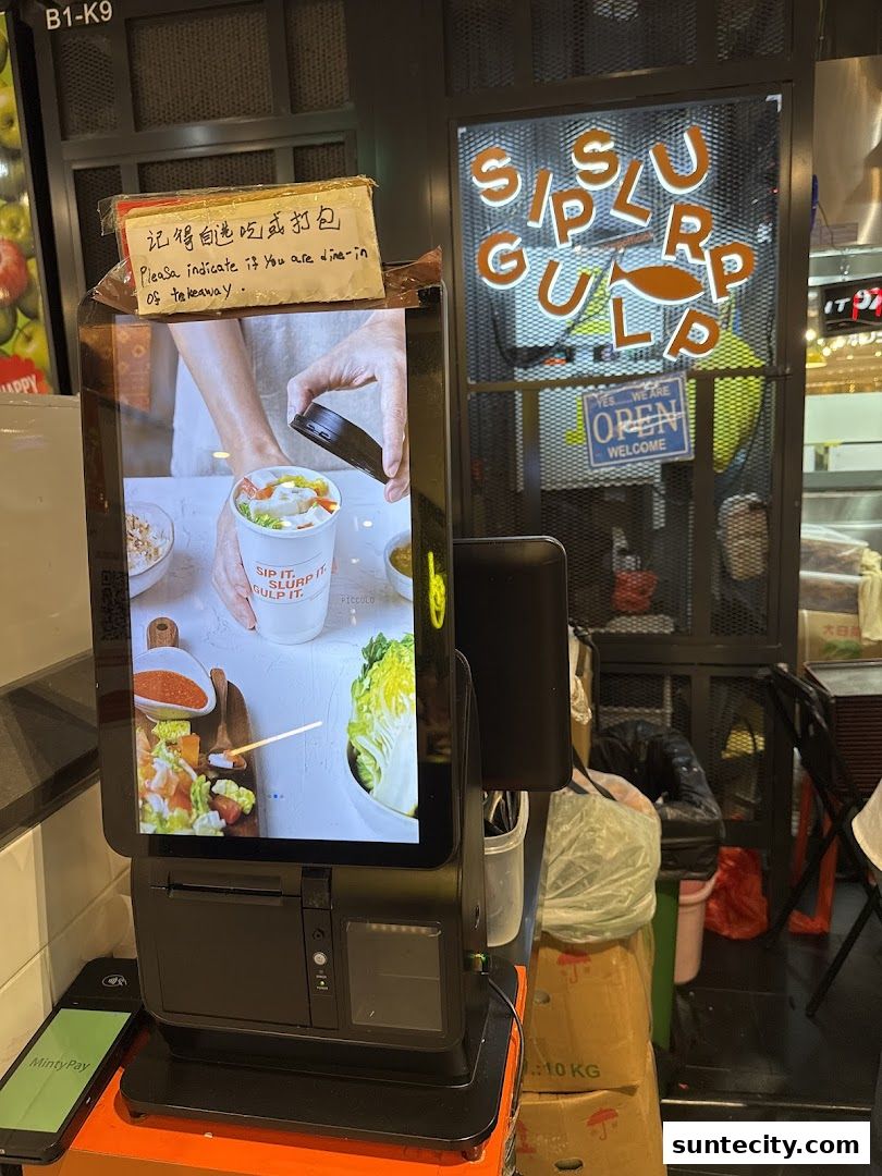 A self-ordering kiosk displays a promotional image of a soup cup with fresh ingredients.