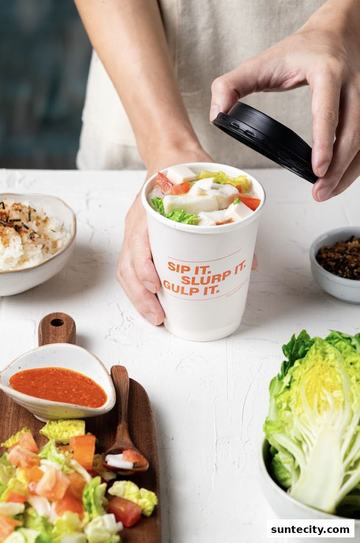 A person is holding a cup of soup with ingredients and a lid.