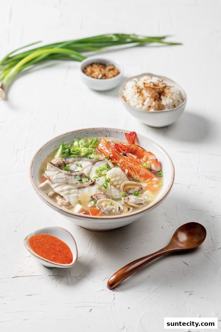 A bowl of seafood soup with fish, shrimp, clams, and squid, served with rice and chili sauce.