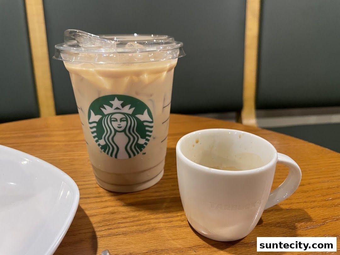 A Starbucks iced coffee and a small espresso cup sit on a wooden table.