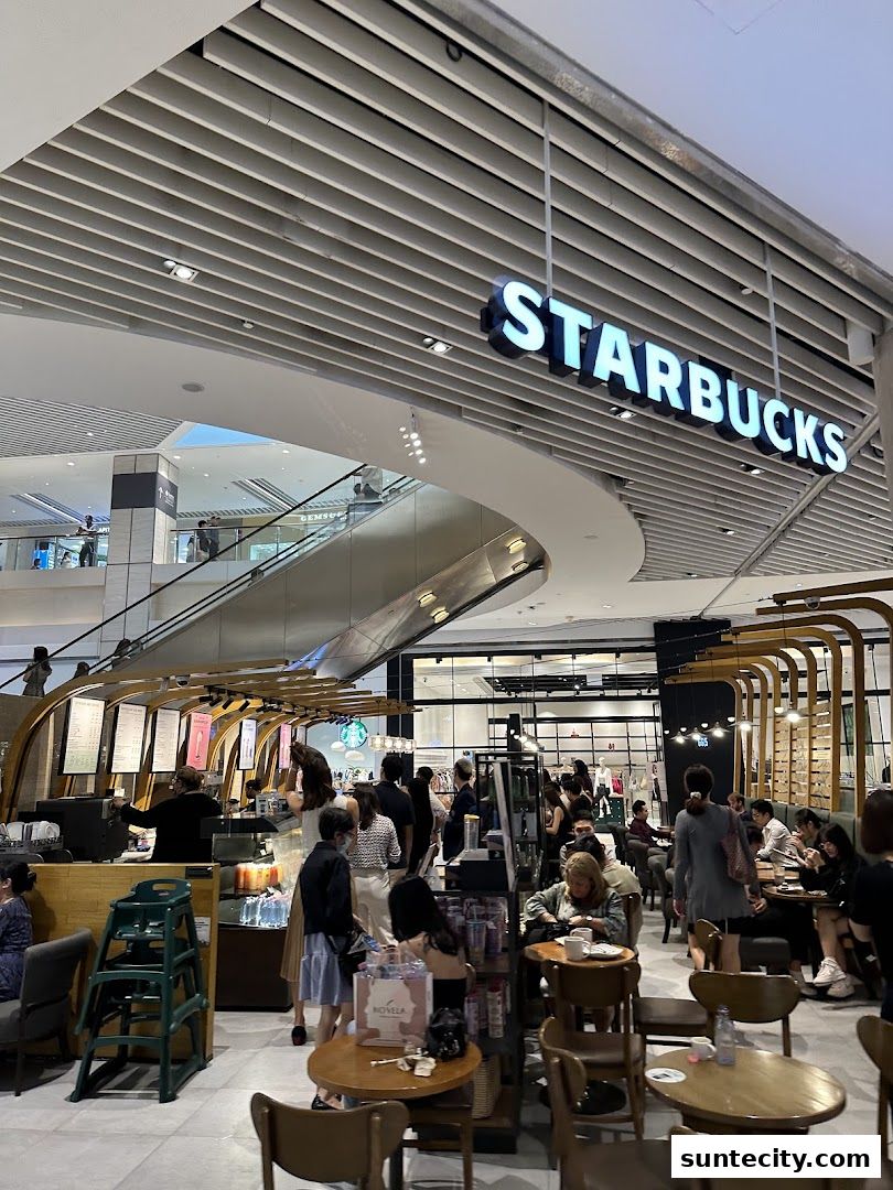 A busy Starbucks cafe with customers ordering and sitting at tables.