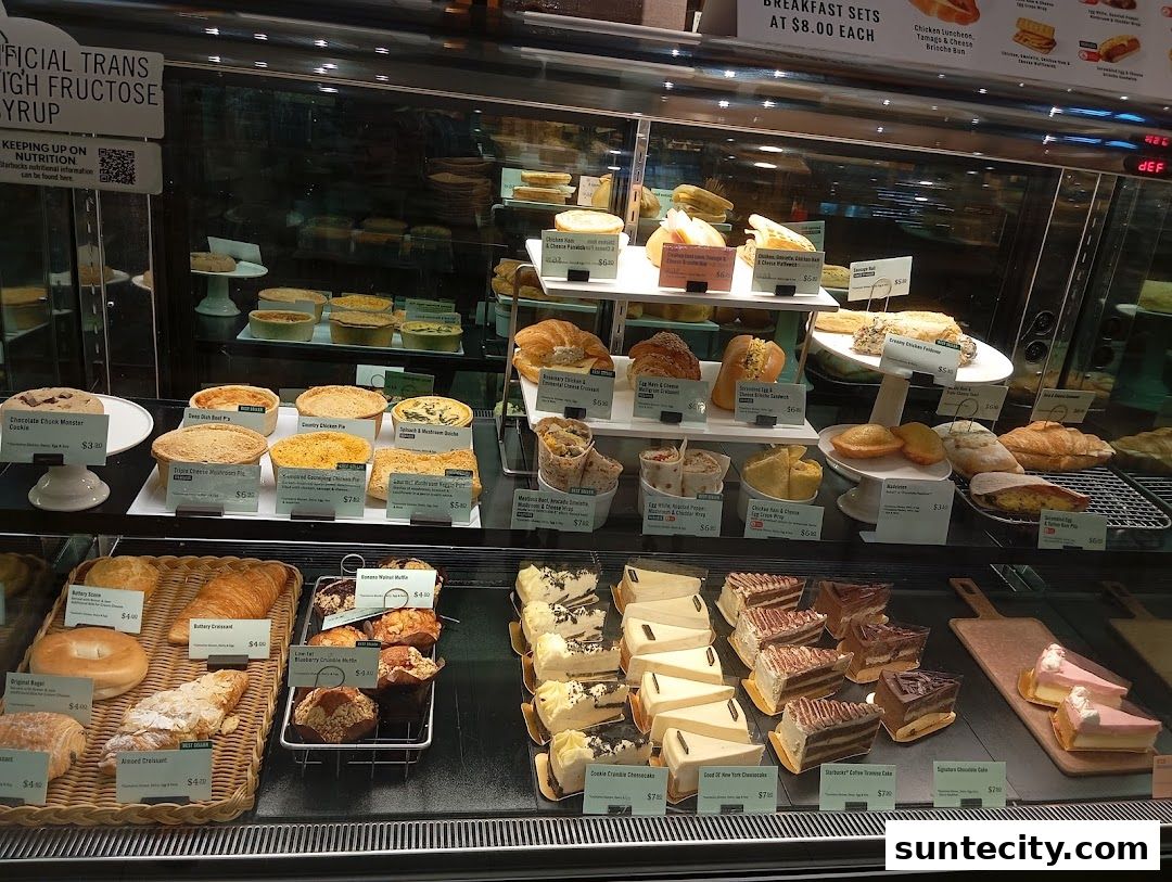 A display case filled with various pastries, cakes, pies, and sandwiches at Starbucks.