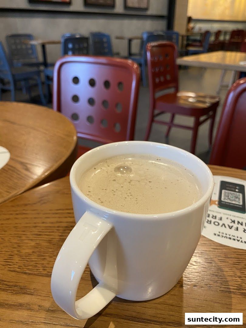 A close-up of a white mug filled with a frothy beverage on a wooden table.