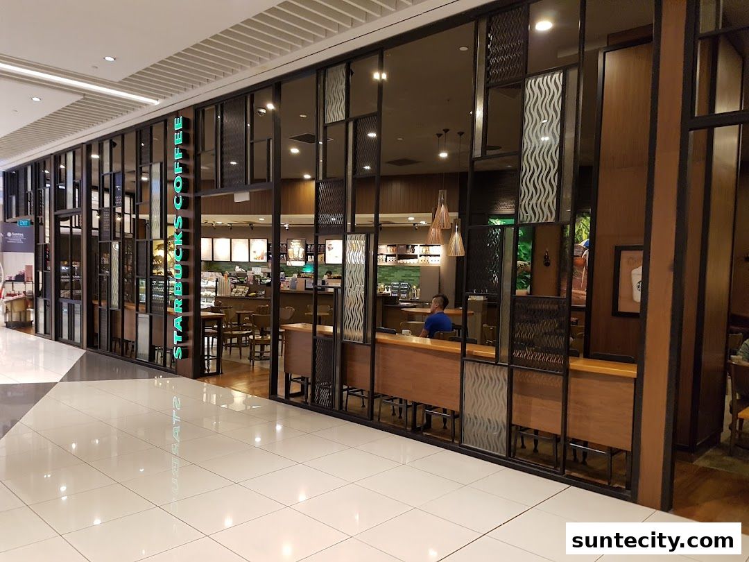 The exterior of a Starbucks coffee shop with large glass windows and wooden accents.