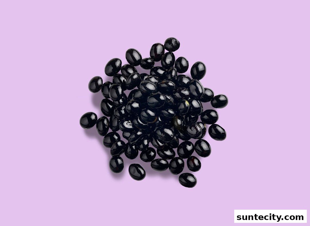 A pile of glossy black beans on a light purple background.