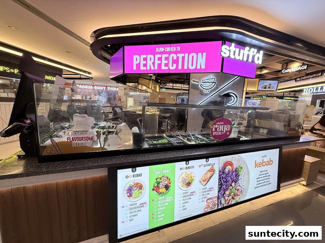 A food stall with a bright pink sign and a menu display showcasing kebabs and bowls.
