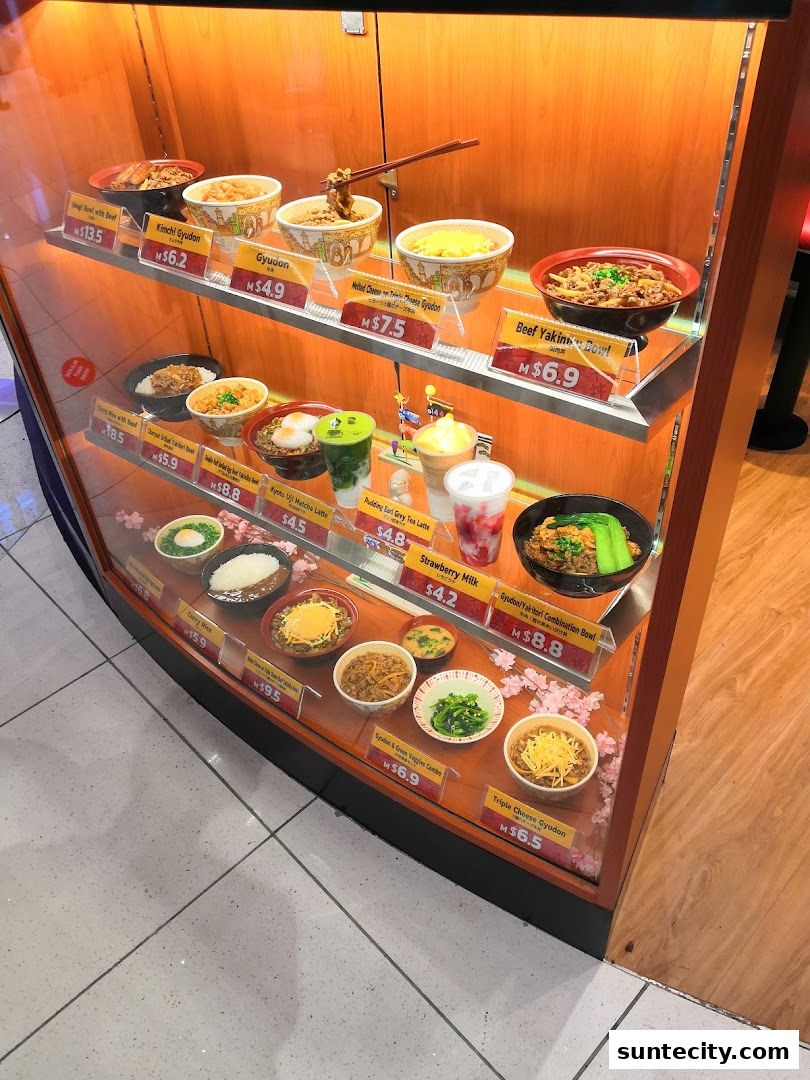 A display case showcasing various Japanese food items and drinks from Sukiya.