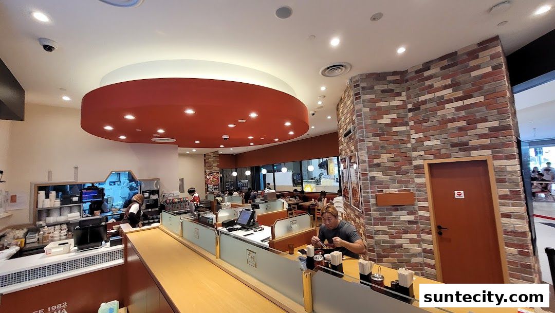 Interior view of a Sukiya Gyudon restaurant with customers dining and staff behind the counter.