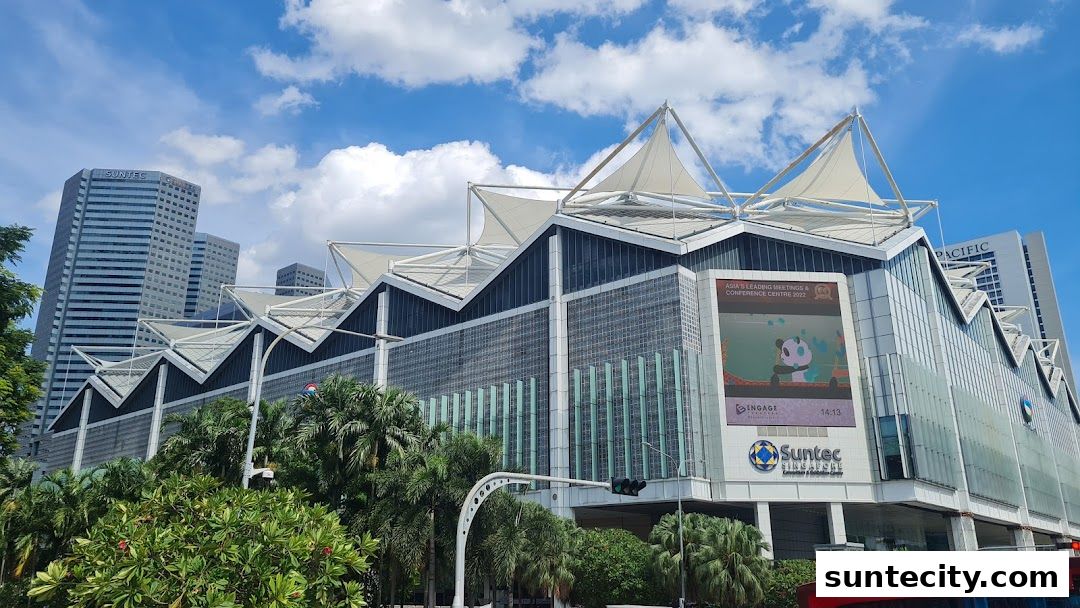 The Suntec City building with its distinctive peaked roof and glass facade under a blue sky.