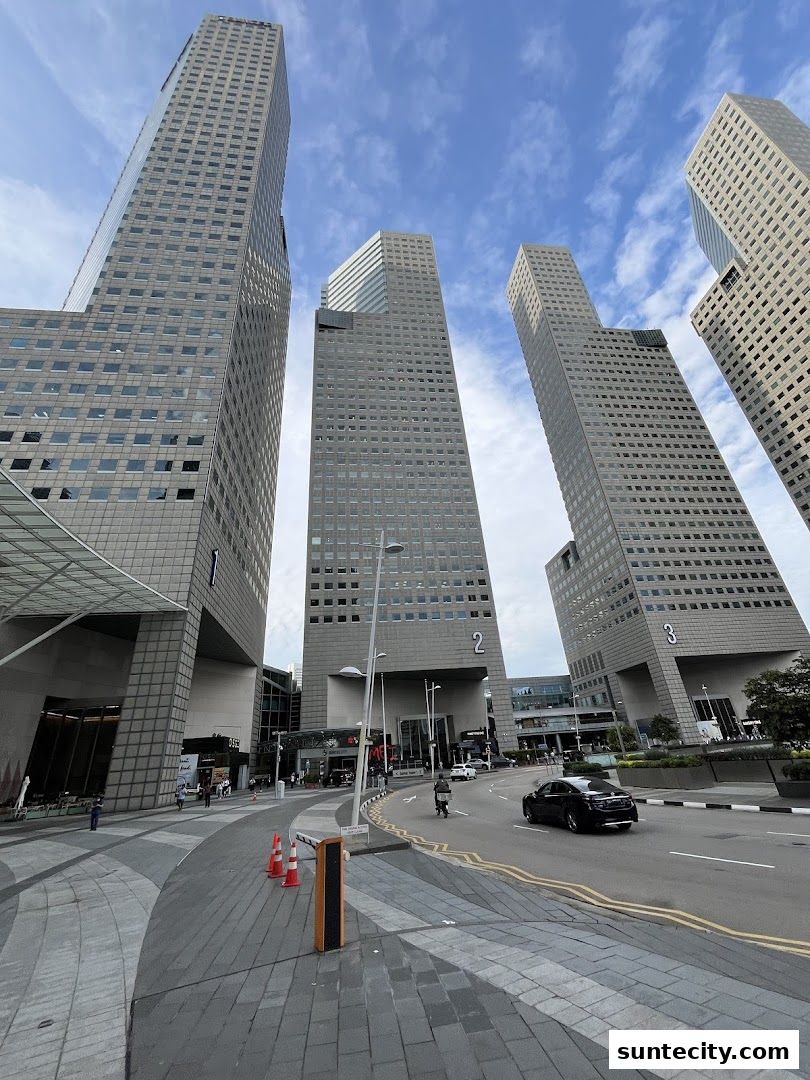 A view of the Suntec City complex with several tall office buildings under a cloudy sky.