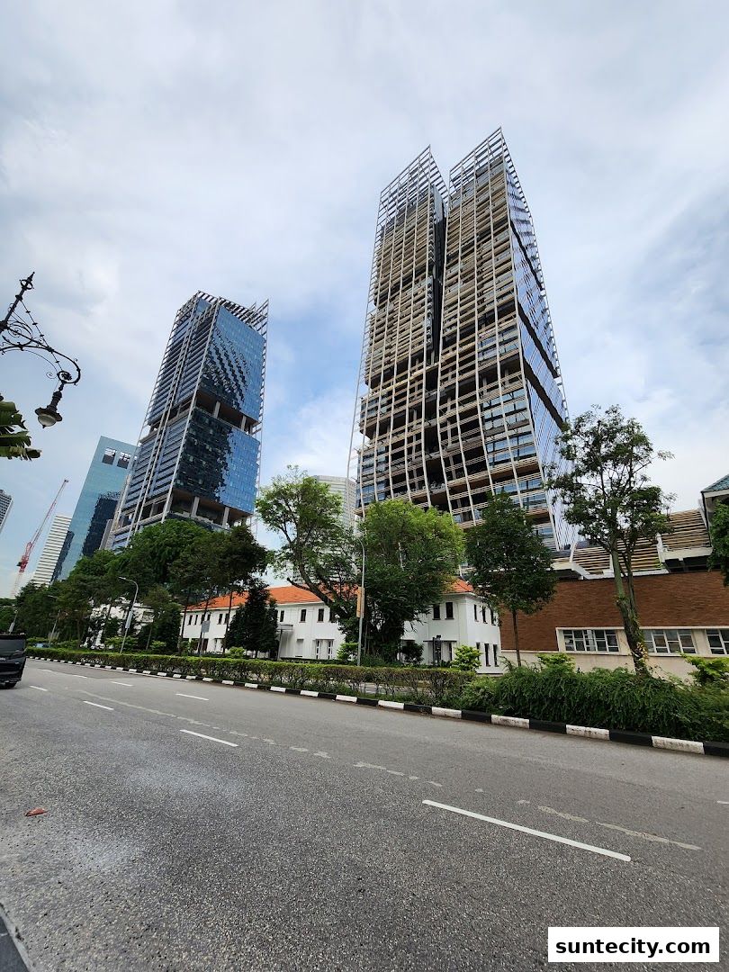 Modern skyscrapers and low-rise buildings line a street under a cloudy sky.