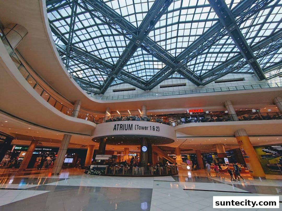 Interior view of a modern shopping mall with a large glass ceiling and multiple levels.