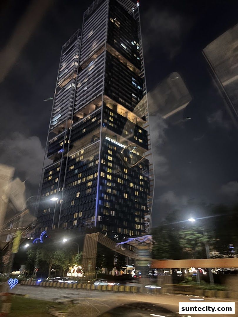 A tall, modern skyscraper at night, illuminated with many windows and signage.