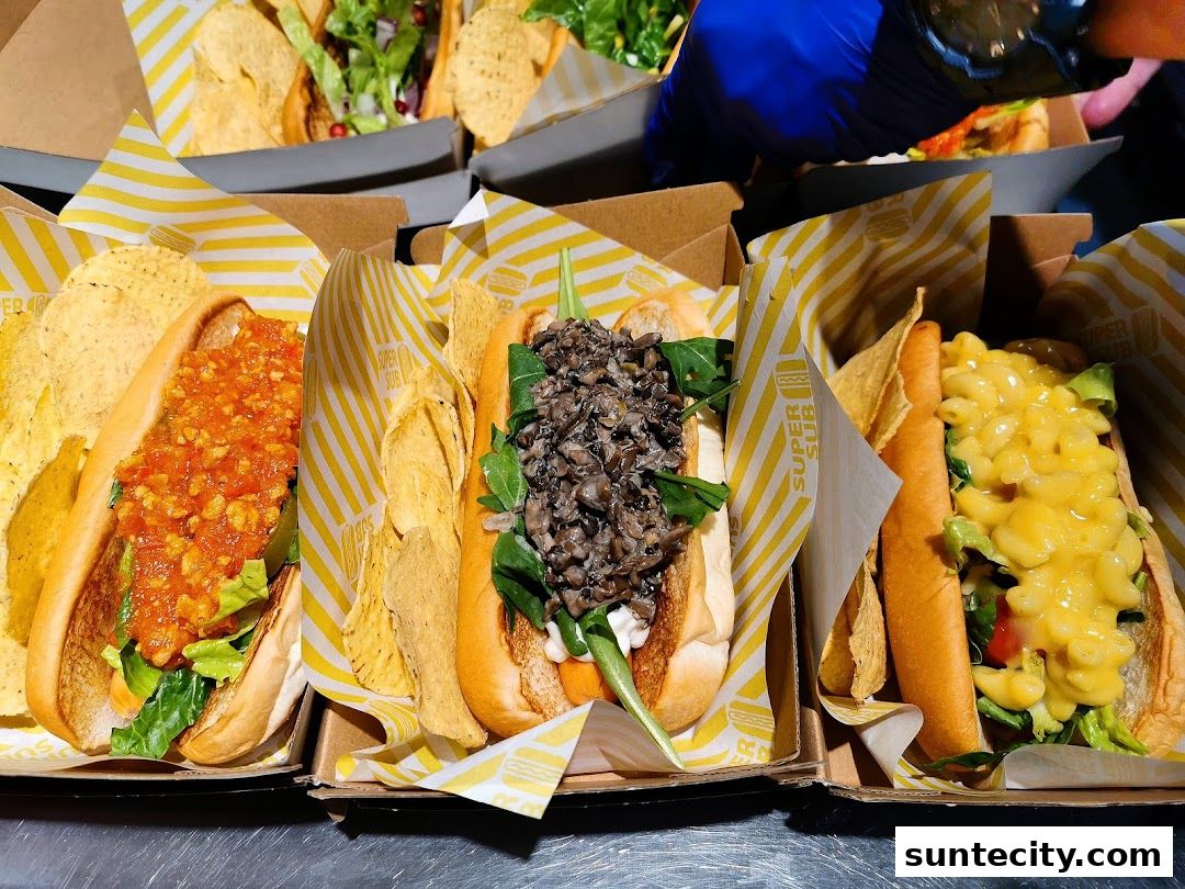 Three delicious hot dogs with various toppings and a side of chips are presented in boxes.