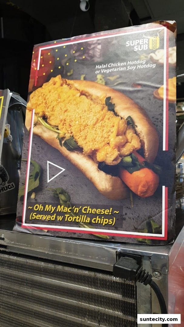 A close-up of a Super Sub hotdog with mac and cheese topping and tortilla chips.