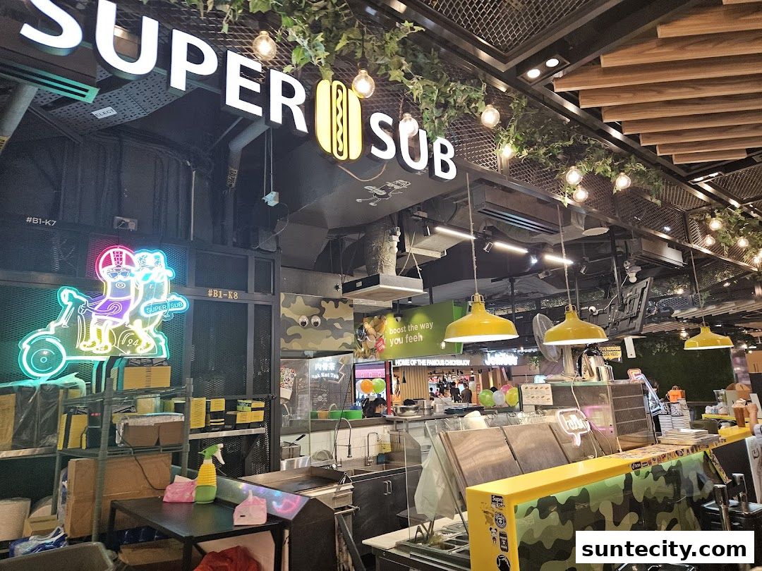 The exterior of Super Sub Hotdogs & Coffee, featuring a prominent sign and bright yellow pendant lights.