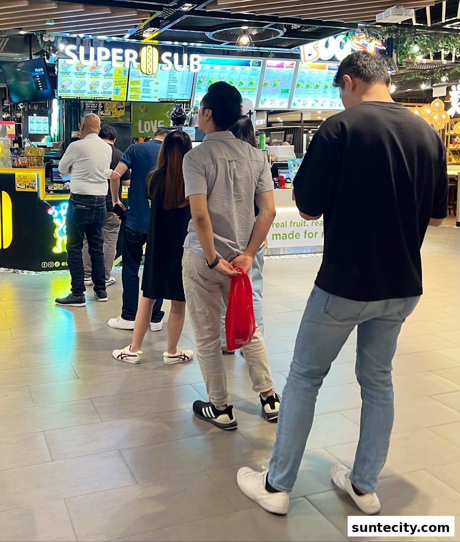 Customers queue at Super Sub Hotdogs Coffee in Suntec City, with menus displayed.
