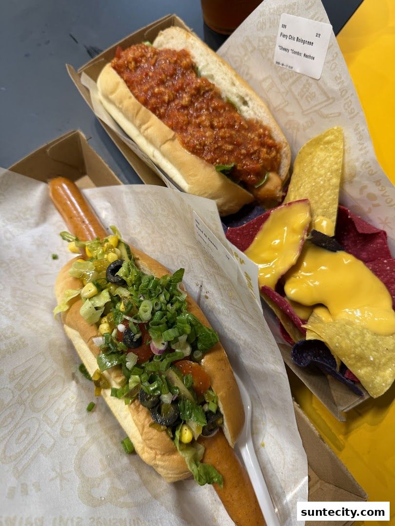 Two gourmet hot dogs and a side of nachos with cheese sauce.