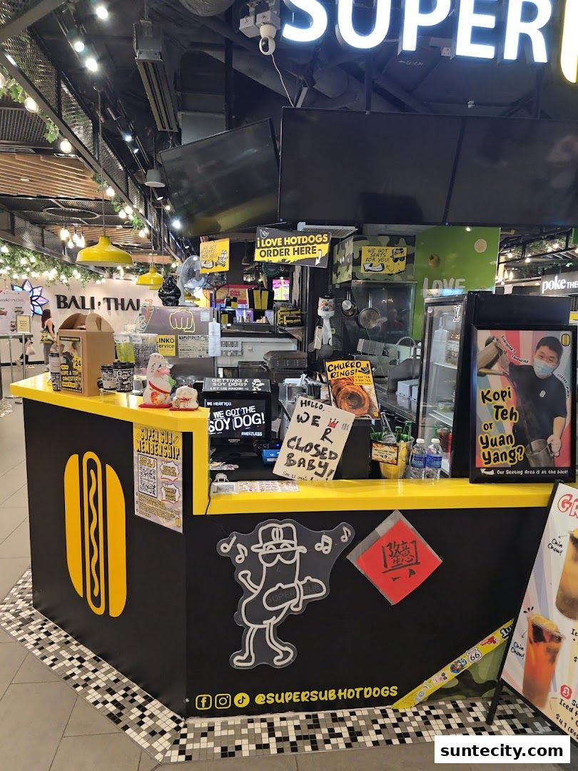 A Super Sub Hotdogs kiosk with bright yellow accents and a prominent hotdog logo.