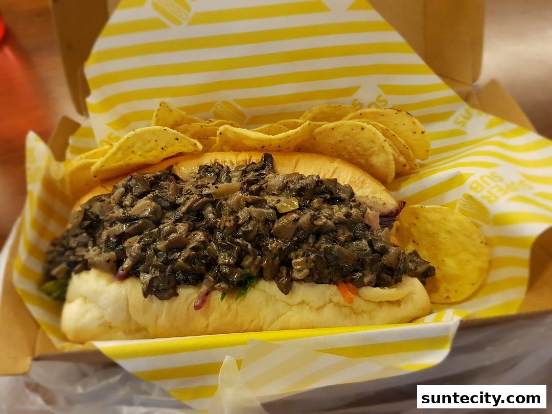 A delicious mushroom sub sandwich served with a side of tortilla chips.
