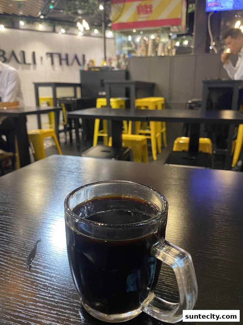 A close-up of a glass mug filled with dark coffee on a black table.