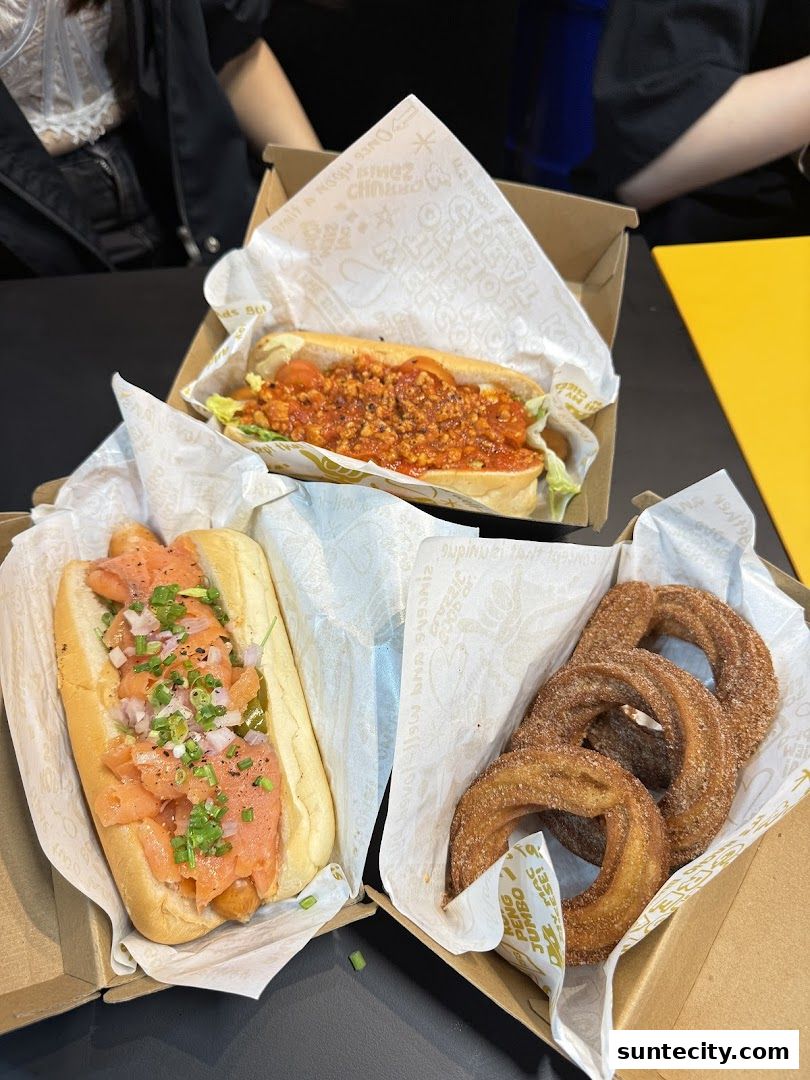 Three boxes of food, including two hot dogs and a serving of churros.