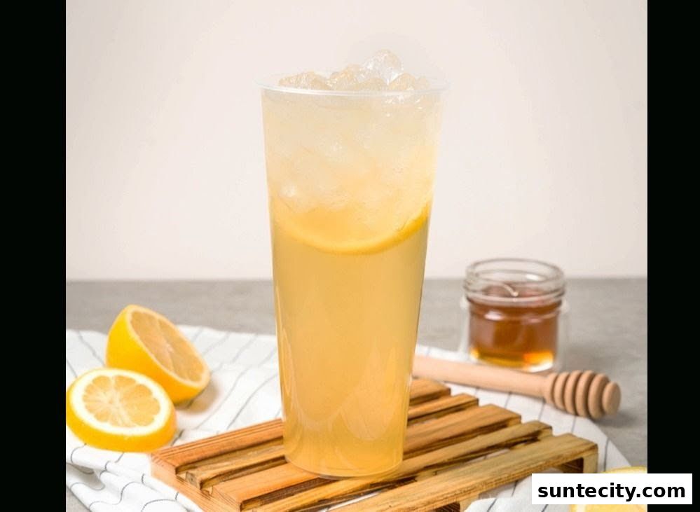 A refreshing honey lemon drink with ice, lemon slices, and a small jar of honey.
