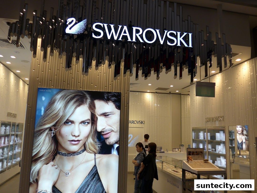 The entrance of a Swarovski store with a large advertisement and display cases.