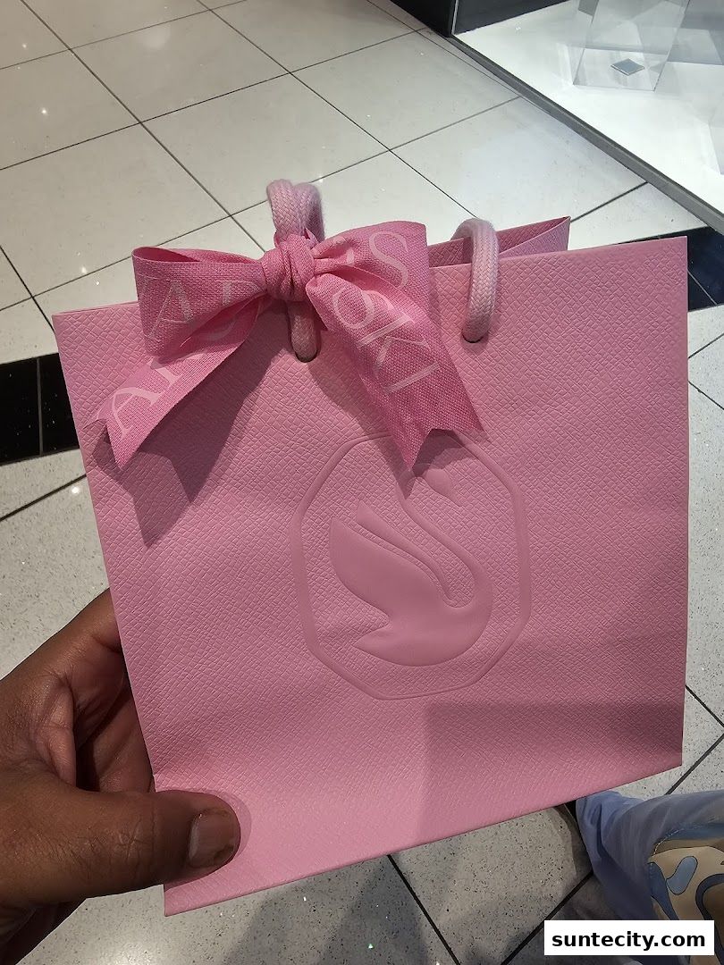 A pink Swarovski shopping bag with a ribbon tied in a bow.