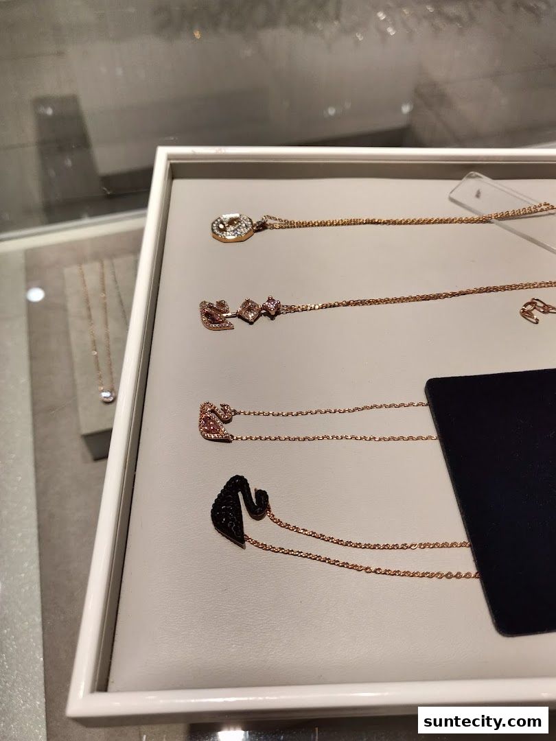A display of elegant Swarovski necklaces featuring swan and geometric designs.