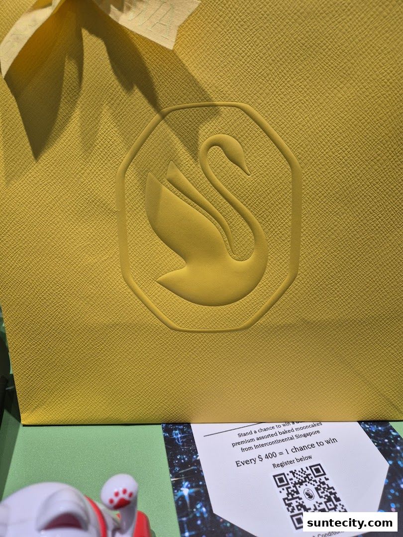 A yellow shopping bag with a swan logo and a promotional flyer.