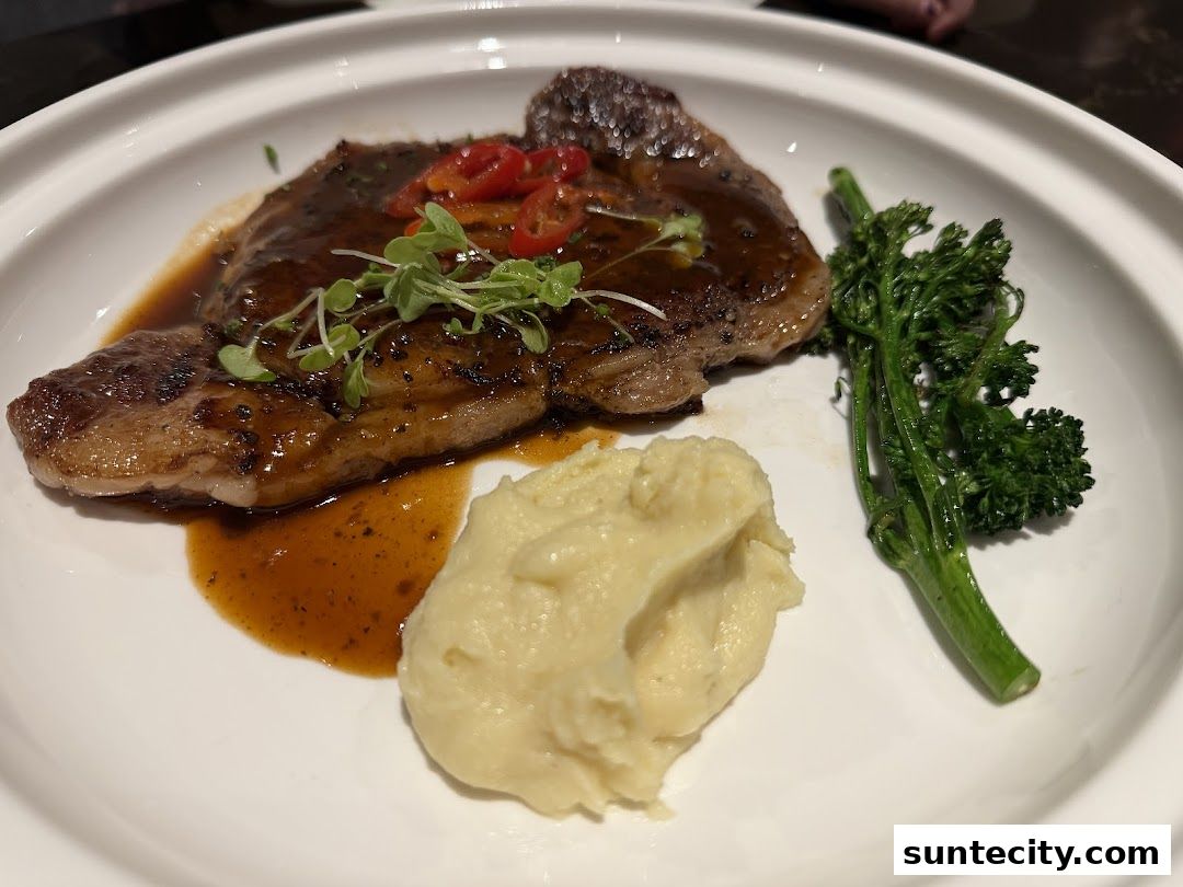 A gourmet steak dish with mashed potatoes and broccolini, garnished with chili and microgreens.