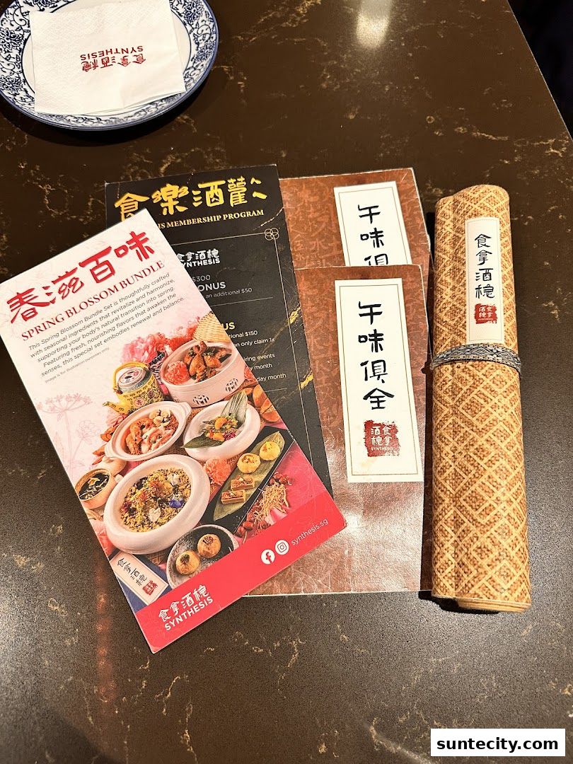 A table setting with menus and a napkin from Synthesis restaurant.