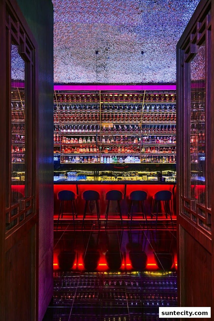 A stylish bar interior with rows of liquor bottles, a lit bar counter, and stools.