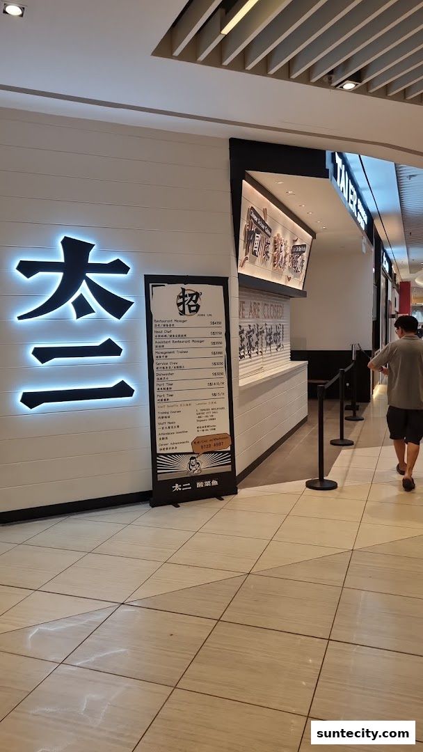 The exterior of a closed restaurant with a large illuminated sign and a job advertisement stand.